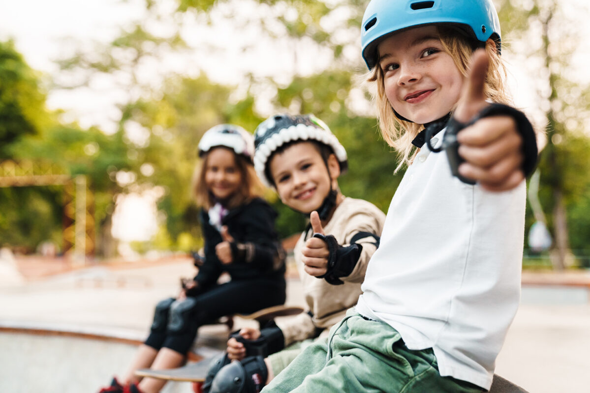 Glada glada barn med skateboards vid rampen ger tummen upp